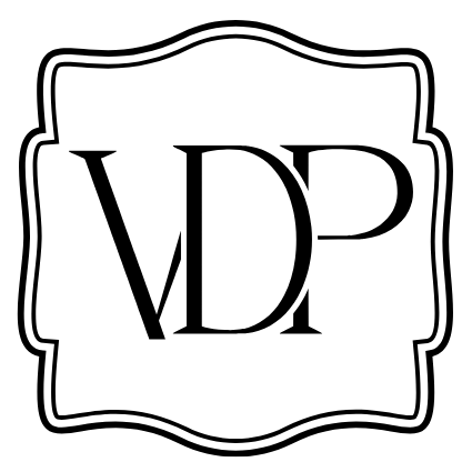 A black decorative monogram logo reading VDP inside a white square frame with a wavy border.